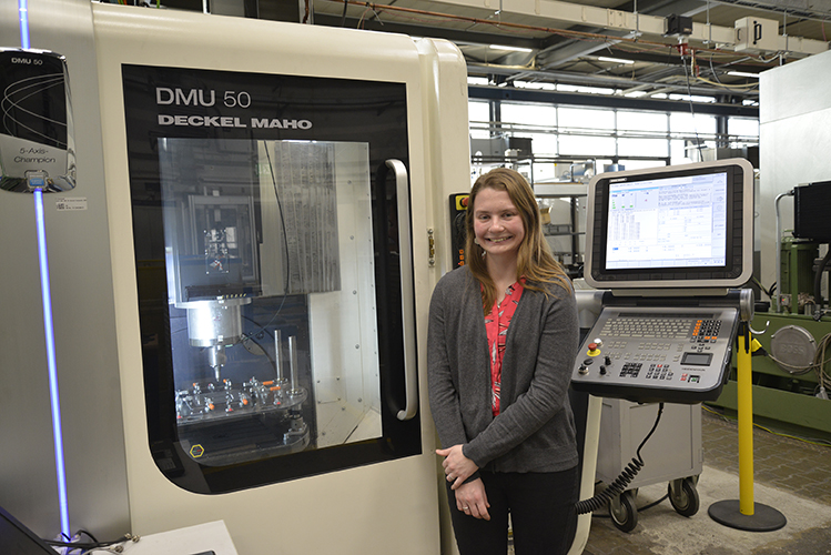 Elizabeth Mamros standing in front of the 5-axis milling machine used for experiments at the IUL - TU Dortmund University, Germany
