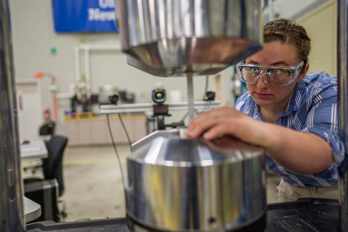 Photo of a college student adjusting an instrument  at the John Olson Advanced Manufacturing Center