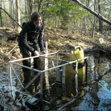 woman working in river with research equipment